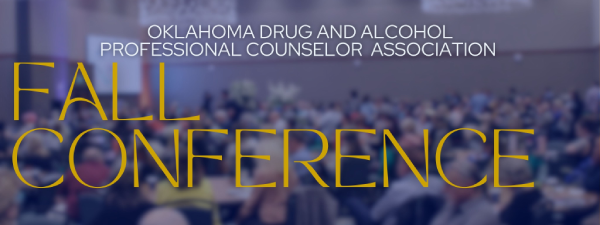 a blurred photo of people at a conference presentation. 'Oklahoma Drug and Alcohol Professional Counselor Association. Fall Conference'