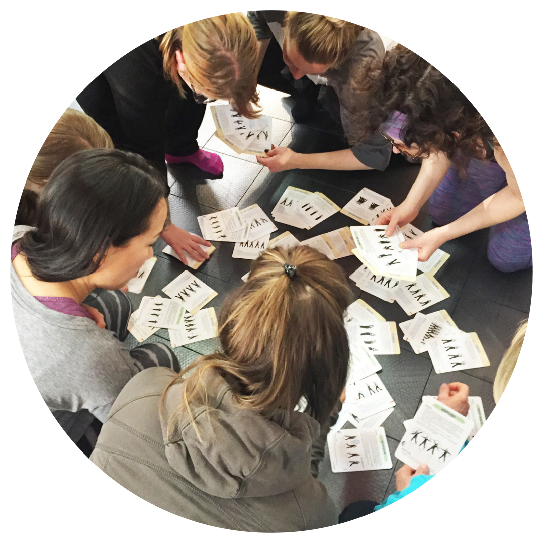 Group of dance instructors sitting in a circle reviewing Rhythm Works Integrative Dance training cards with movement illustrations and teaching strategies.