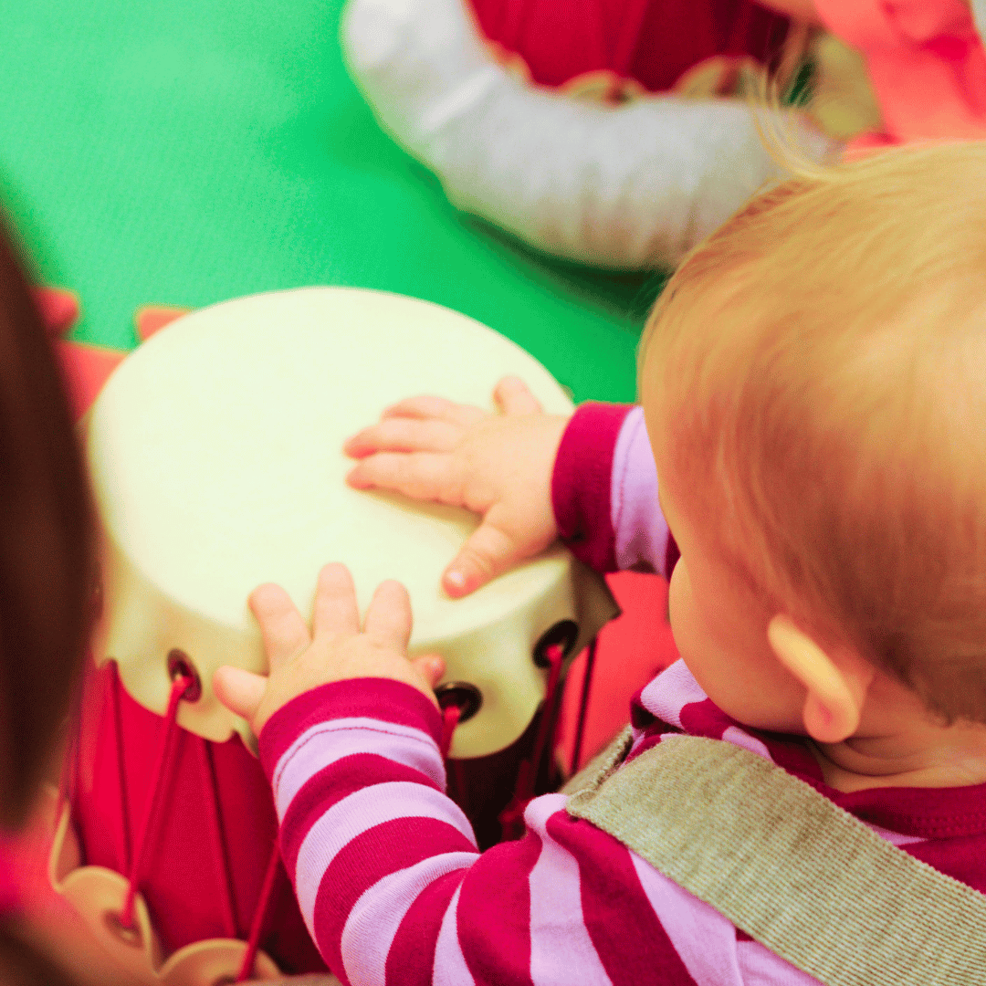 A baby girl playing a drum.