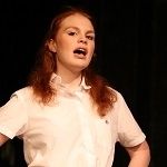 Portrait of Jess Heath wearing a white polo on a black background