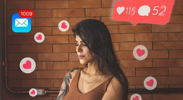 A female with a tattoo in her arm surrounded by virtual notifications and hearts from social media
