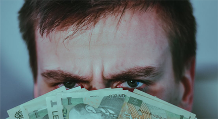 A guy hiding his face in a stack of money