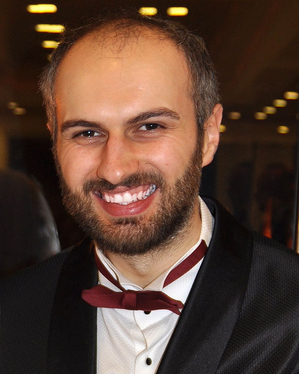 Adrian Tofei - Sophisticated gentleman in black suit and red bow tie, emanating charm and class.