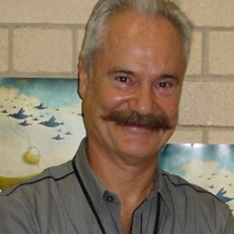 James Lingwood - A middle aged man with white hair and a fully grown moustache wearing a grey polo
