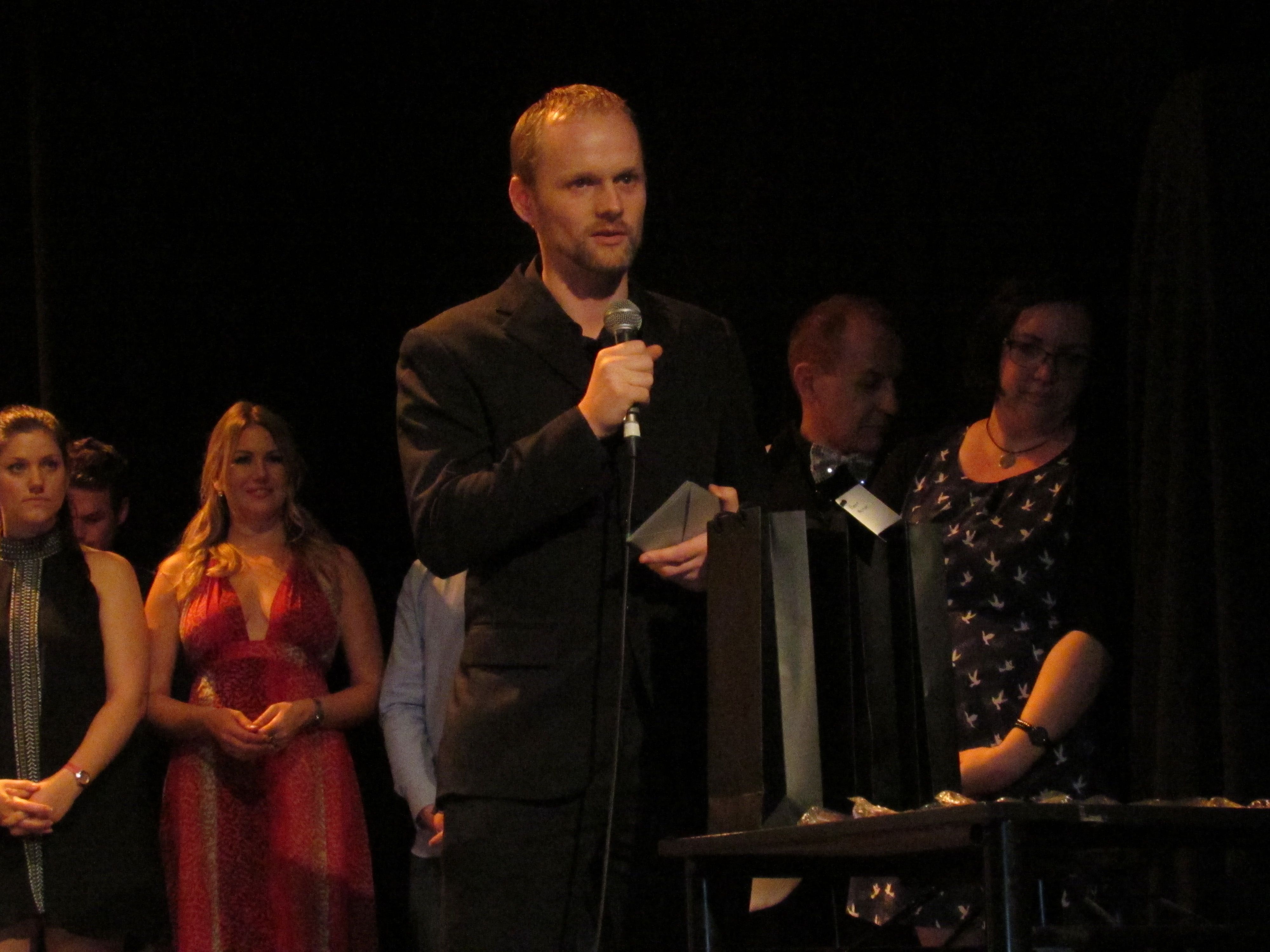 A Portrait Of Pete Malicki in a serious face wearing a gray coat and a navy blue shirt