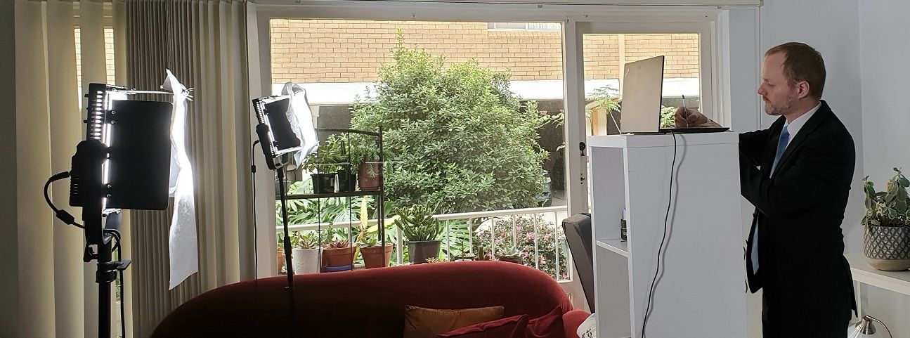  A man in a suit standing in front of a studio television