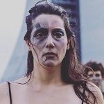 Cris Bocchi, A woman in a black dress with makeup on her face, exuding elegance and confidence.