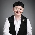 Roxanne Marcelle-Shaw, A woman in a black vest and white shirt standing confidently.