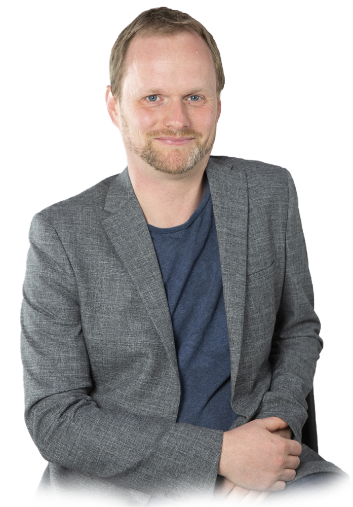 Pete Malicki wearing a grey coat and a navy blue shirt 