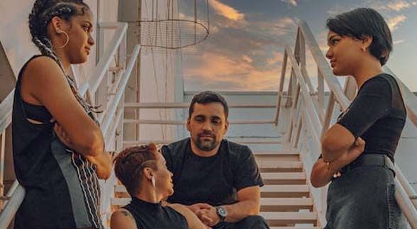 Two woman staring at each other while a man and woman is talking in the middle of them