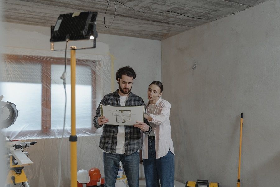 A man and woman standing in a room with construction equipment.