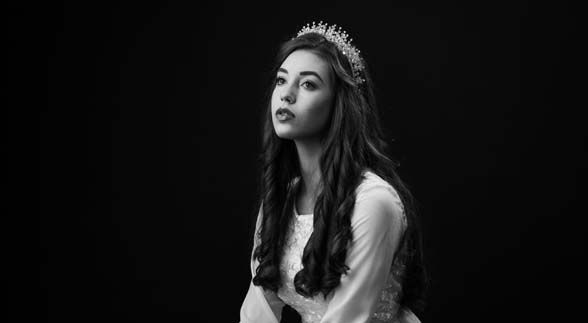 A black and white image of a curly haired woman wearing a tiara and a white dress
