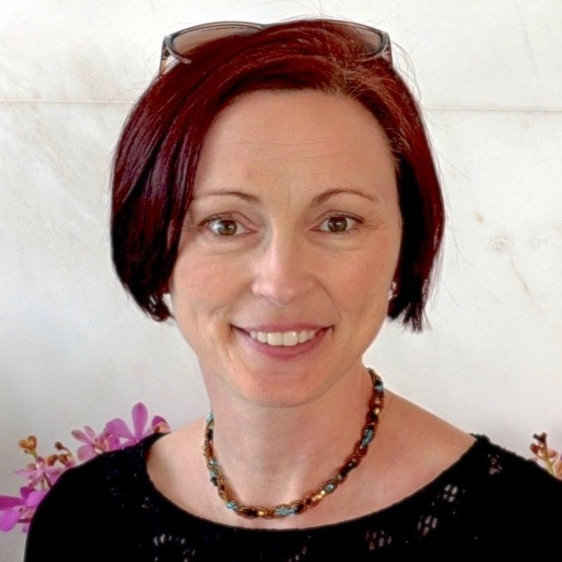 Katherine Hennessey, A short red-haired woman wearing a black blouse and a necklace beads