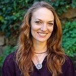 Rose Newland - A woman with a red brown hair, smiling, wearing a violet dress and a necklace with a circle pendant