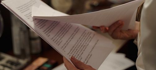 A hand holding a piece of script