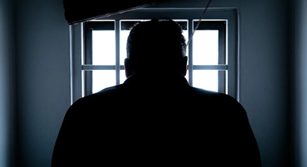 A silhouette of a guy inside a cell facing the window lights
