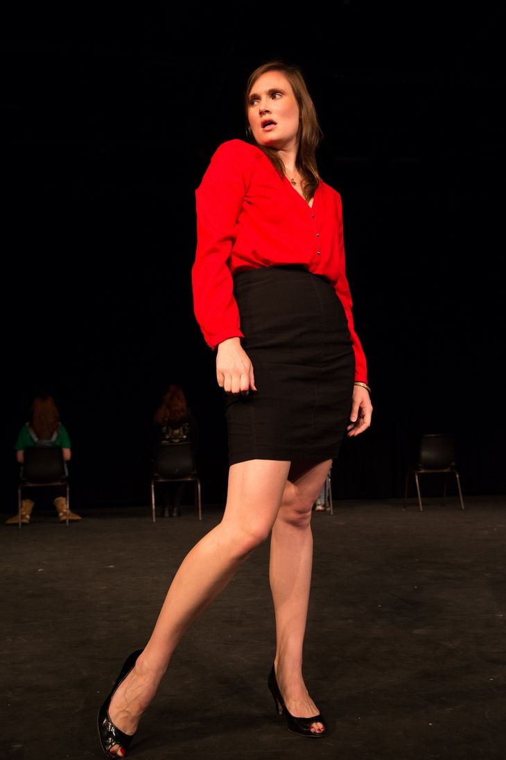 Female actor on stage wearing red blouse and black skirt