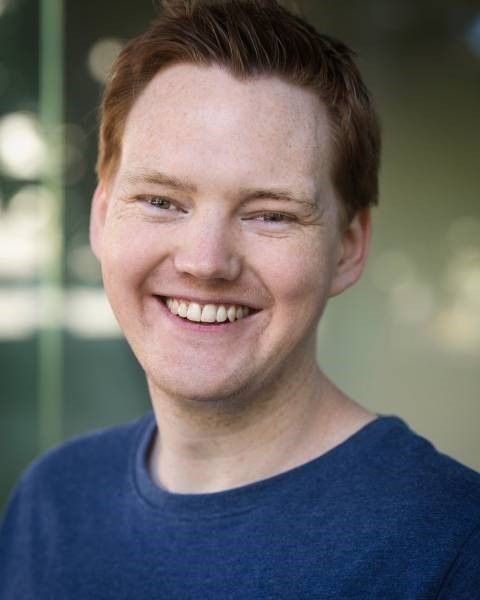 Brendan Kelly - A man with red hair smiling, radiating warmth and happiness.