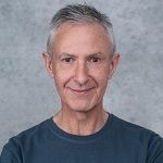 Matt Ruglys, An elderly man with grey hair wearing a blue t-shirt.