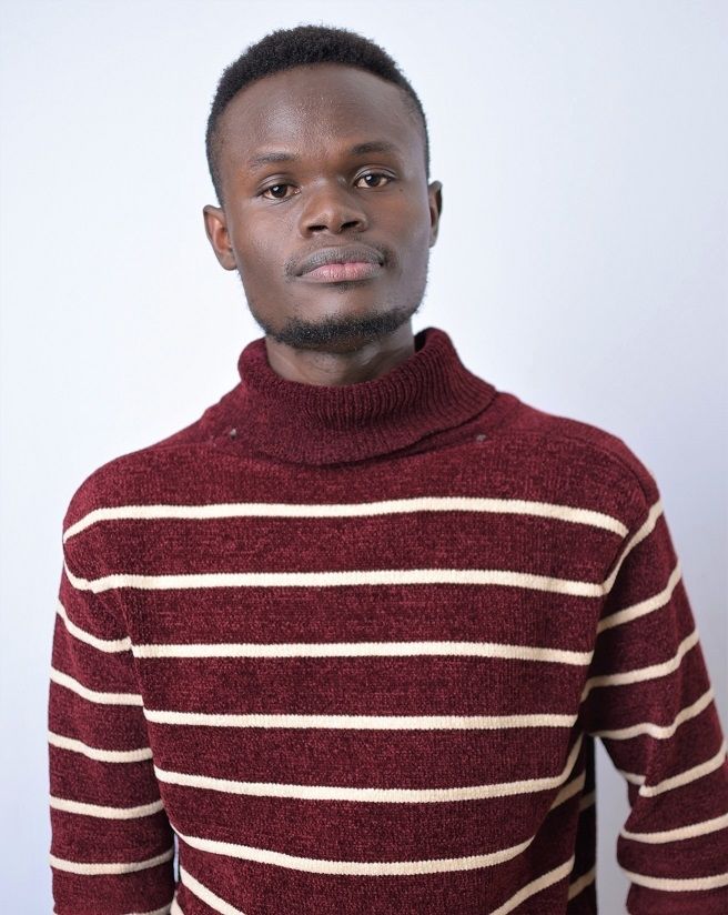 Joseph Obel - A shorty curly haired man wearing a striped maroon turtle neck sweatshirt