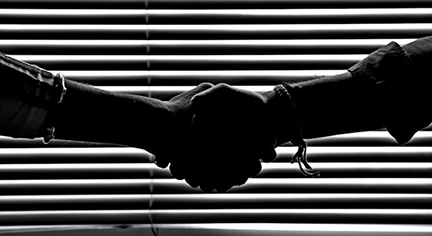 A silhouette of two people shaking hands