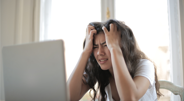 A female that is devastated in front of a monitor