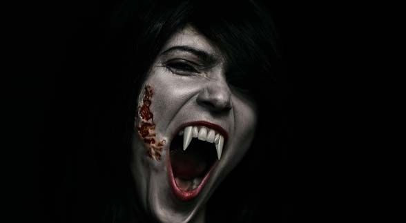 A woman vampire with scar on her cheek while opening his mouth and showing her huge fangs