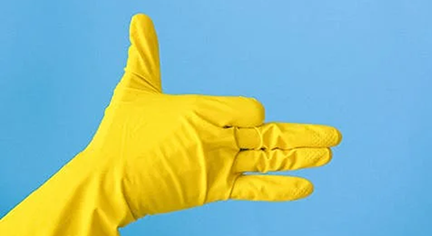 A hand wearing a yellow glove doing a symbol of a dog