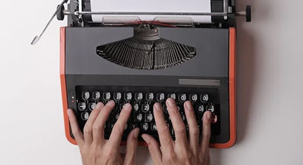 A hand typing in an old typewriter