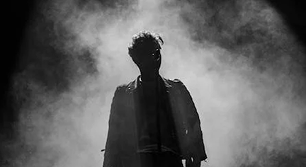 A silhouette of a guy in stage with fogs all over the place