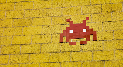 A pixelised game bug in a yellow bricked wall