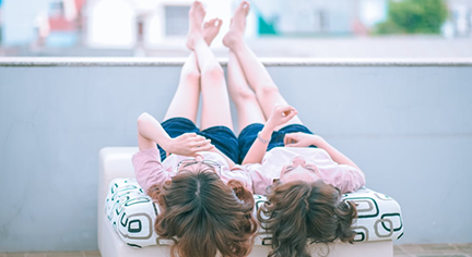 Twins laying down in the rooftop while looking at the sky