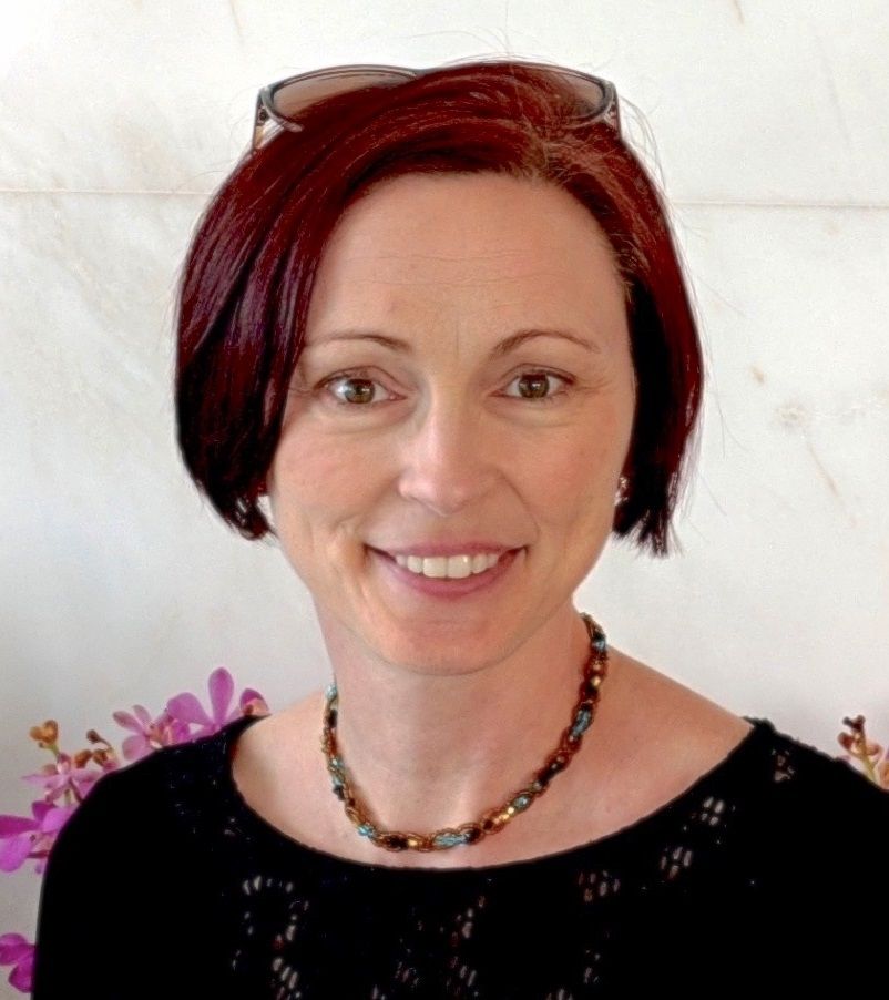Katherine Hennessey, A short red-haired woman wearing a black blouse and a necklace beads