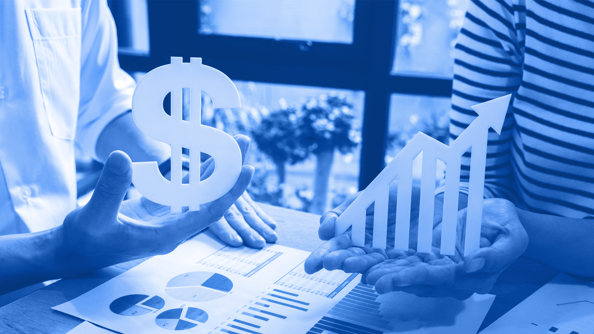 Two people talking to each other while holding a dollar sign and a graph figure