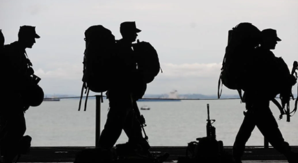 A silhouette of soldiers carrying their arms and packs to the battle field