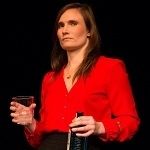 Portrait of Eliza St John wearing Red blouse holding an empty glass and bottle on a black background
