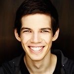 Portrait of Atlas Adams smiling on a brown background