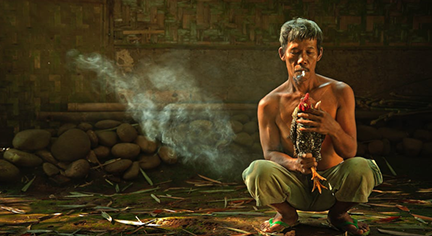 A man holding a rooster while smoking a cigarette