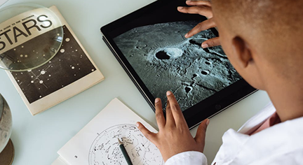 A man studying about the moon in his tablet