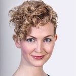 Portrait of O'Sullivan smiling with curly hair on a white background