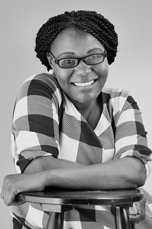 Chipo Basopo - A woman with braided hair wearing a glasses and a checkered blouse