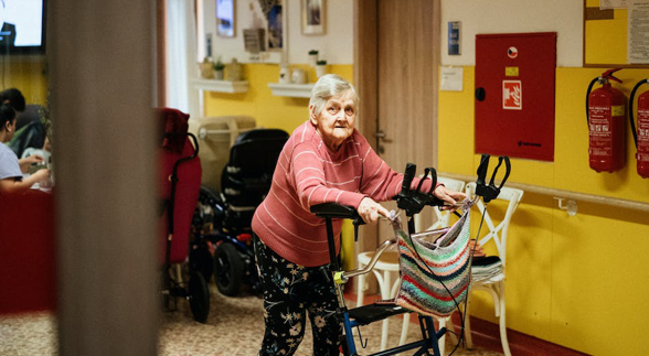 A Grandmother holding her stand support inside a nursing home with yellow walls