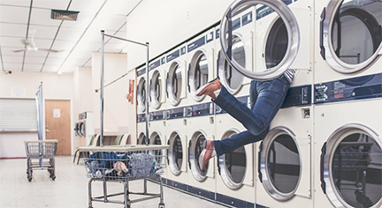 A woman loading the laundry machine with half of her body inside it