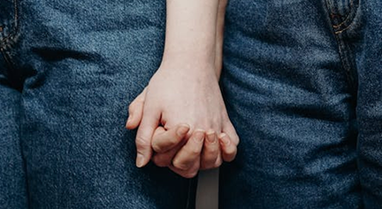 A couple holding hands and both of them are wearing jeans