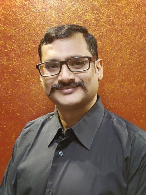 E Kalyan Babu - A short haired Indian with a mustache wearing a glasses and a dark gray colored formal sleeves