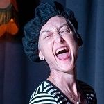 Susan Mattocks - A woman with wide open mouth wearing a black beret and a stripe green and white shirt