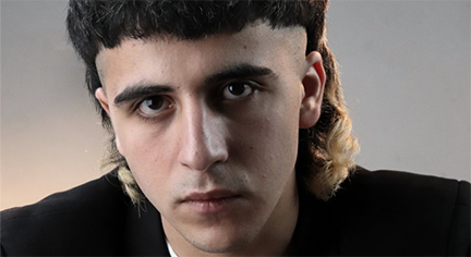 A man with a mullet hairstyle facing the camera fiercely