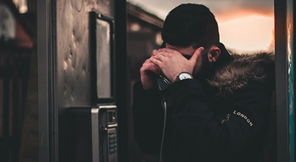 A man that looks problematic while talking in a phone booth