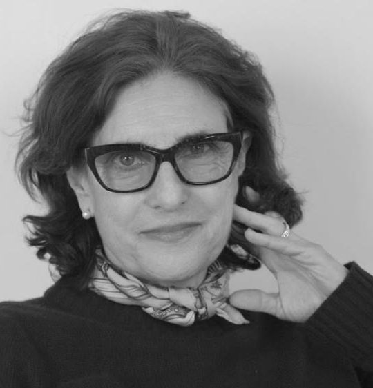 Avy Kaufman - A black and white image of a middle aged woman wearing glasses, black sweater and a scarf