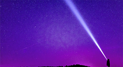 A man in a horizon pointing out a flashlight to the sky
